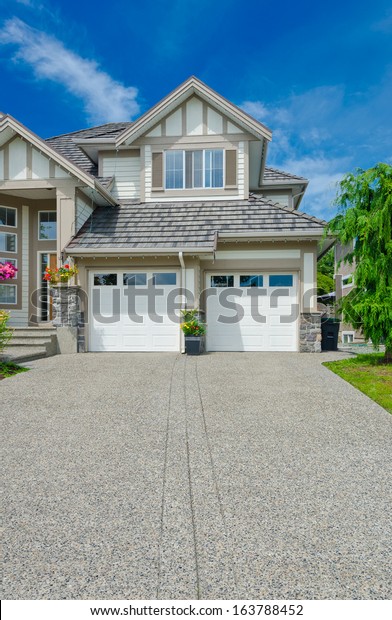 Double doors garage with wide and long\
driveway  in the suburbs of Vancouver,\
Canada.