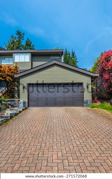 Double doors garage with wide, nicely\
paved driveway. North America. Canada.\
Vertical.