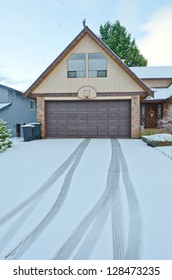 Double Doors Garage Winter Time With Tire Tracks On The Long Driveway