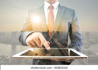 Double Exporsure Of Business Man Working With A Digital Tablet On City Scape Background,investment And Networking Concept