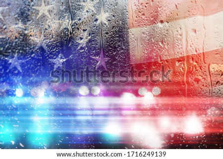 Double exposure of American flag and police cars on street at night