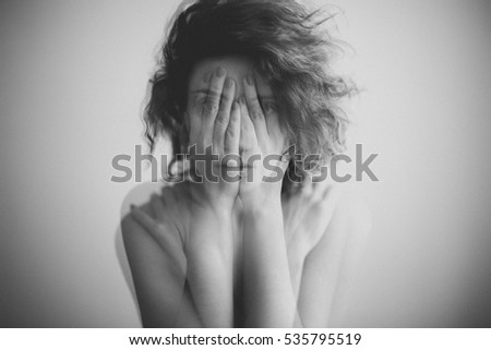 Double exposure black and white portrait of a woman covering her face and eyes with her hands 