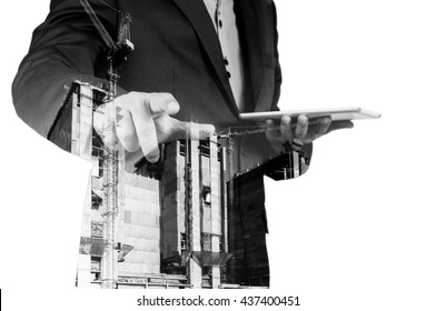 Double exposure of Business Man with Digital Tablet and Power Crane in the City as Construction Project concept.