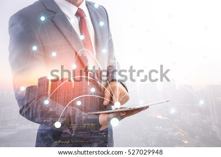 Double exposure of a businessman and a city using a tablet, cityascape and network concept