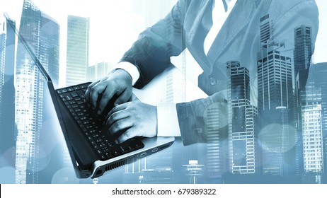 Double exposure of businessman working on laptop or notebook with Cityscape background. Mixed media.
