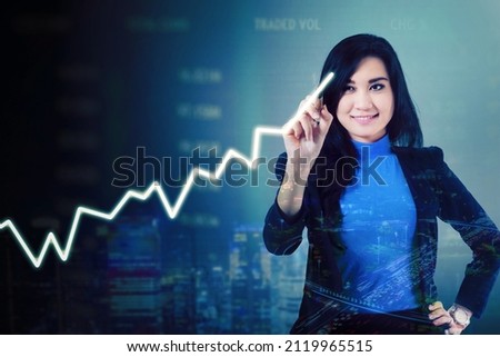 Double exposure of businesswoman drawing upward arrow while standing with stock market background