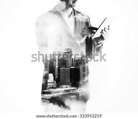 Double exposure of city and businessman using digital tablet