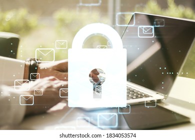 Double exposure of creative lock hologram with email symbols and hands typing on laptop on background. Information security concept