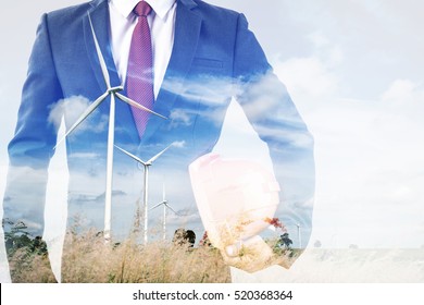 Double Exposure Of Engineer Or Worker Hold In Hand Yellow Helmet For Workers Security With Wind Turbine Green Energy Plant Background 