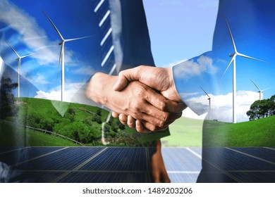 Double Exposure Graphic Of Business People Handshake Over Wind Turbine Farm And Green Renewable Energy Worker Interface. Concept Of Sustainability Development By Alternative Energy.