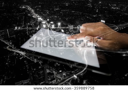 double exposure hand using tablet and city on night background