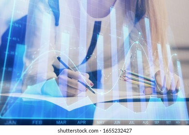 Double exposure of hands making notes with forex chart huds. Stock market concept.