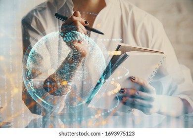Double exposure of hands making notes with world map hologram and data theme icons. Concept of international network data.