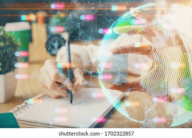 Double exposure of hands making notes with world map hologram and data theme icons. Concept of global computer data.