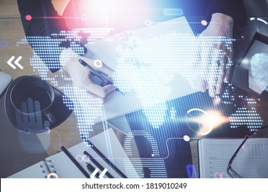 Double exposure of hands making notes with world map hologram and data theme icons. Concept of global computer data.