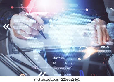 Double exposure of hands making notes with world map hologram and data theme icons. Concept of global computer data.