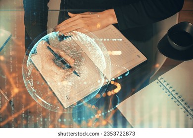 Double exposure of hands making notes with world map hologram and data theme icons. Concept of global computer data.