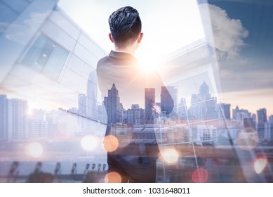 The Double Exposure Image Of The Business Man Standing Back During Sunrise Overlay With Cityscape Image. The Concept Of Modern Life, Business, City Life And Internet Of Things.