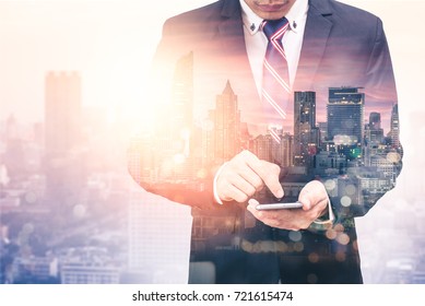 The double exposure image of the business man using a smartphone during sunrise overlay with cityscape image. The concept of modern life, business, city life and internet of things. - Powered by Shutterstock