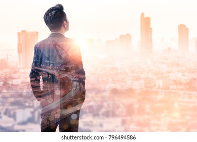 The Double Exposure Image Of The Business Man Standing Back During Sunrise Overlay With Cityscape Image. The Concept Of Modern Life, Business, City Life And Internet Of Things.