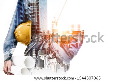 Double exposure image of construction worker holding safety helmet and construction drawing against the background of surreal construction site in the city.