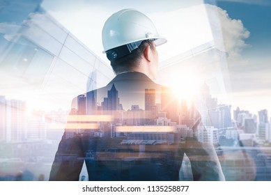 Двойное изображение инженера, стоящего назад во время восхода солнца, с изображением городского пейзажа. Концепция инжиниринга, строительства, городской жизни и будущего.