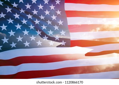 Double exposure image of the wing of an airplane at sunset and the American flag, representing travel. 