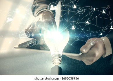 Double exposure of man's hands holding and using a digital device and bulb hologram drawing. Idea concept.