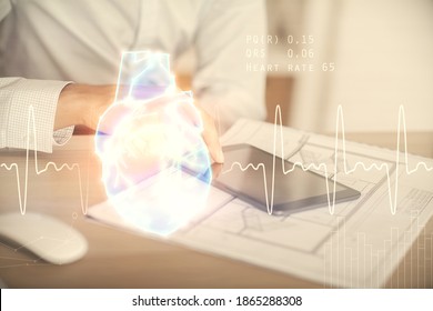 Double exposure of man's hands holding and using a phone and heart drawing. Medical education concept.