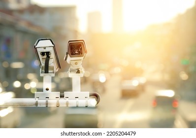 Double exposure of modern public CCTV camera on traffic roads at sunset background with copy space - Shutterstock ID 2205204479