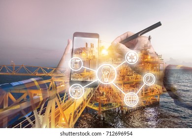 Double exposure photo, hand touching mobile phone for using business tool icons,with oil & gas platform  background for industrial 4.0 concept.