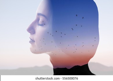Double exposure photo with woman silhouette and sunset sky with mountains and birds. Freedom and travel concept - Shutterstock ID 556500076
