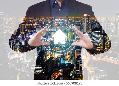 Double Exposure Property Management Concept - Businessman Show House Symbol Between Hands With City Overlay