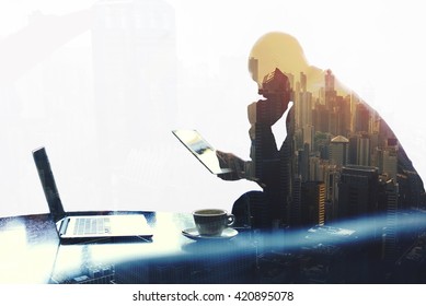 Double exposure silhouette of man skilled managing director is analyzing activities of the company by using touch pad and net-book. Thoughtful economist is reading news in network via digital tablet - Powered by Shutterstock