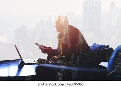 Double exposure silhouette of successful businessman is working in office company with net-book and touch pad. Thoughtful entrepreneur is using digital tablet and laptop computer for finance analyze