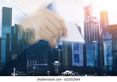 Double exposure of success businessman holding bank business card with city landscape and background.