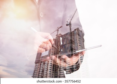 Double exposure of success businessman using digital tablet with Construction site with crane and building