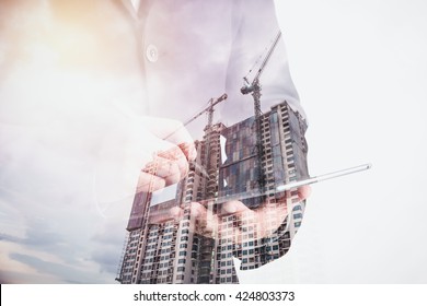 Double exposure of success businessman using digital tablet with Construction site with crane and building - Powered by Shutterstock