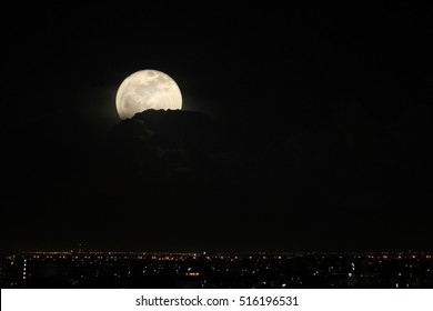 Double Exposure Of Super Full Moon On Cloudy Night Sky And City.