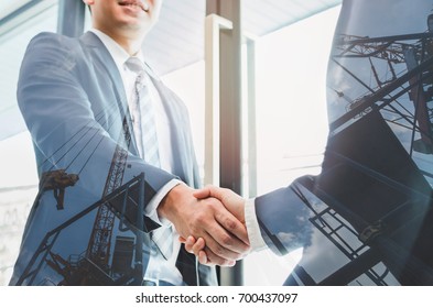 Double exposure of two businessmen reaching an agreement and making handshake with abstract construction site - Greeting and dealing real estate business concepts.