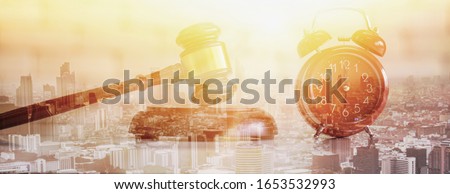 Double exposure-auction wood hammer and pink retro alarm clock, sunset cityscape background,auction control and business concept