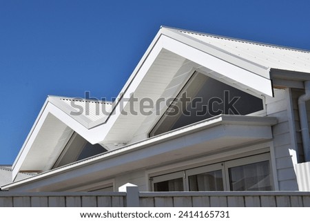 DOUBLE GABLED ROOFLINE ANGLES INSERTED WITH FEATURE TRIANGULAR WINDOWS  - Modern architectural style metal joined twin gable and M shape valley roof line with large rafter windows and an awning below