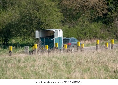 double horse box trailer behind a grey VW Tiguan SEL SUV car passing a Tank crossing in green countryside