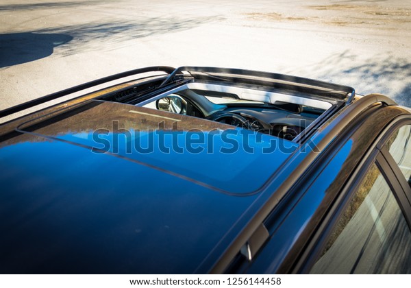 Double panoramic glazed dach\
open sunroof outside view. Tilted, open hatch - luxurious modern\
car isolated photo session in a parking lot. Close up photo,\
detailed.