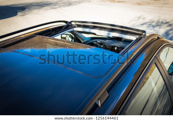 Double panoramic glazed dach
open sunroof outside view. Tilted, open hatch - luxurious modern
car isolated photo session in a parking lot. Close up photo,
detailed.