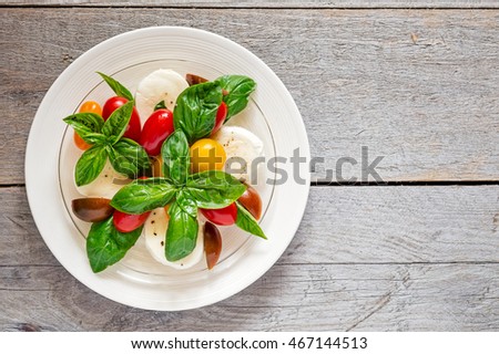 Double plated fresh farm style caprese salad on a weathered wooden board