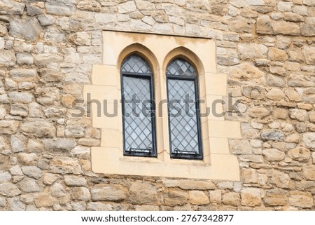 Double pointed arched window with leaded glass in a medieval ancient stone wall