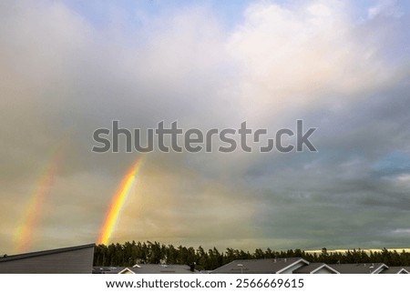 Double rainbow against cloudy sky