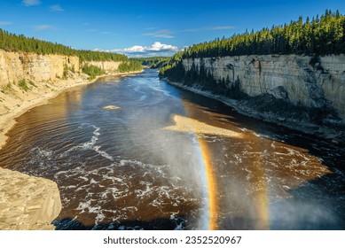 A double rainbow forms in the spray as the Hay River cascades over Alexandra Falls