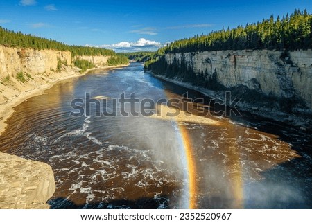 A double rainbow forms in the spray as the Hay River cascades over Alexandra Falls